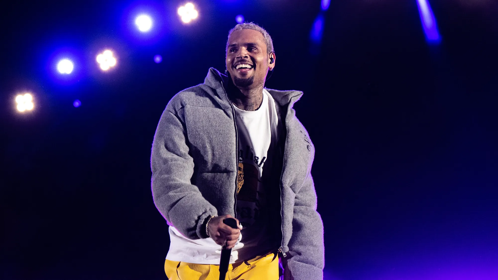 Chris Brown​ in⁣ Amsterdam, wearing a Nike tech suit, standing in front of the National Monument.
