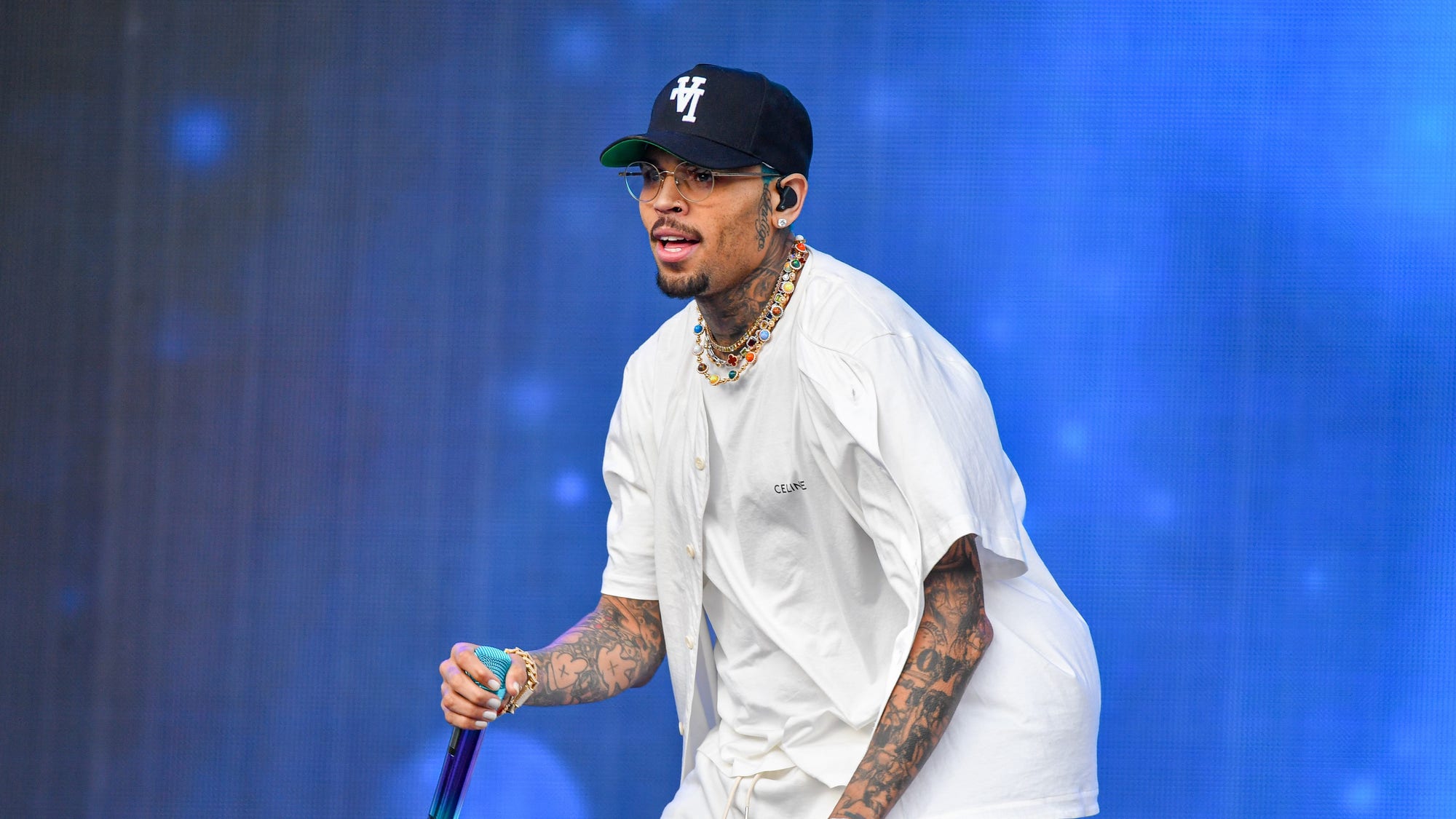 Chris⁣ Brown performing⁣ on ‍stage, bathed ⁢in light.